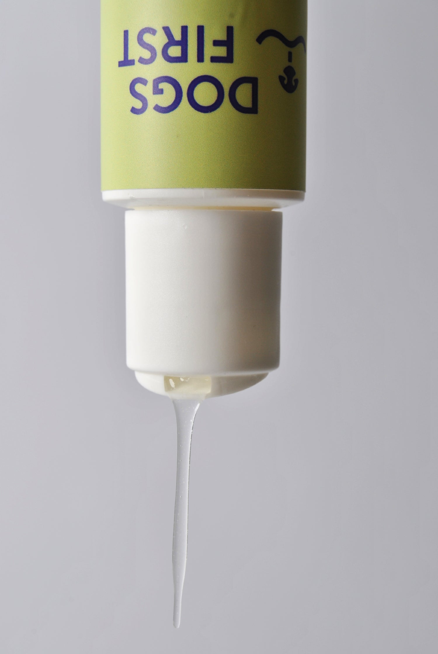 Squeeze dog shampoo bottle with a green label on a gray background dripping shampoo.
