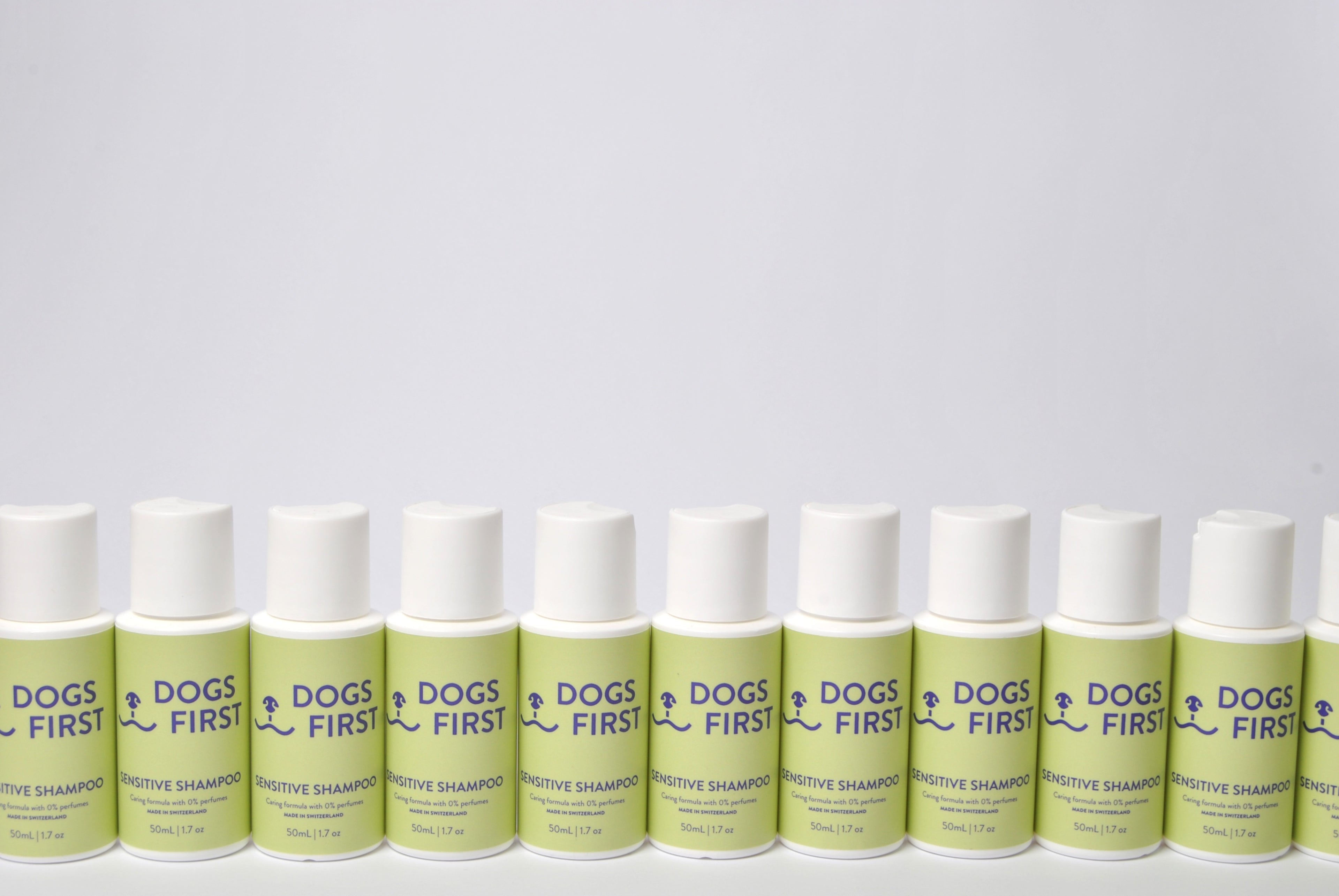 Row of 'Dogs First' dog shampoo bottles on a light gray background
